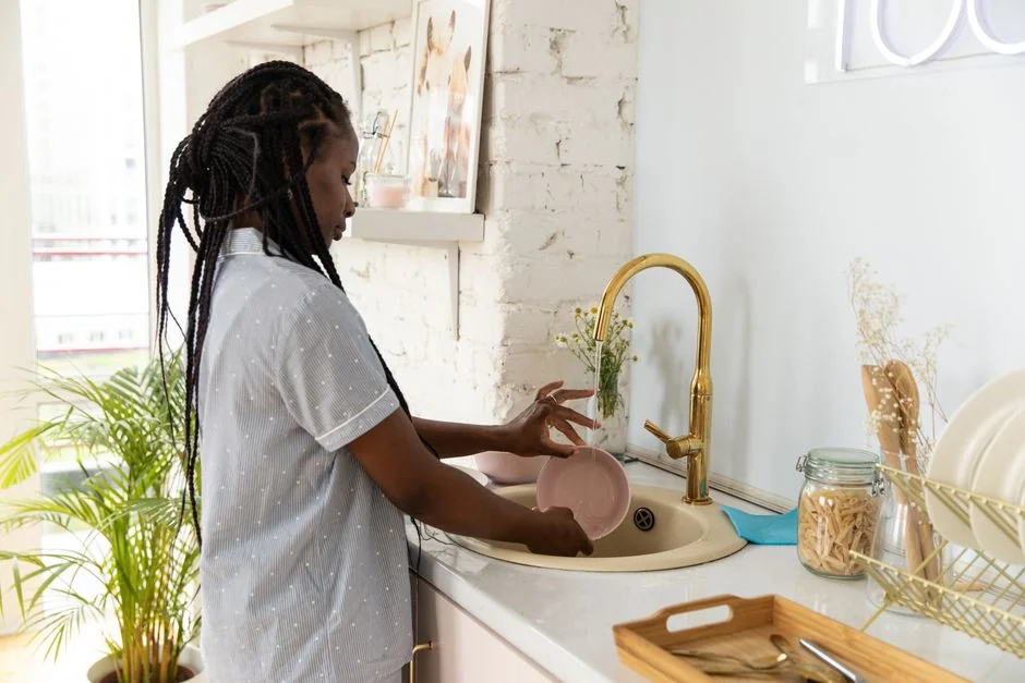 Seen from above, a cropped anonymous person wearing rubber gloves uses a soapy sponge while cleaning a toilet bowl